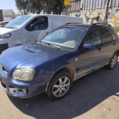 רכב כחול חונה ליד קיר עם גרפיטי