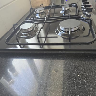 כיריים גז שחורות עם ארבעה מבערים וכפתורי שליטה