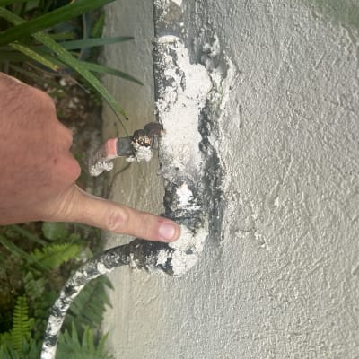 יד מצביעה על צינור עם חלודה על קיר