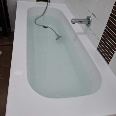 אמבטיה עם מים, ברז וכיסוי קיר חום-לבן