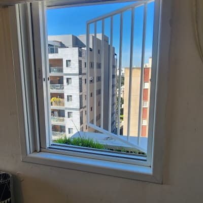 חלון פתוח עם מסגרת לבנה וסורגי מתכת