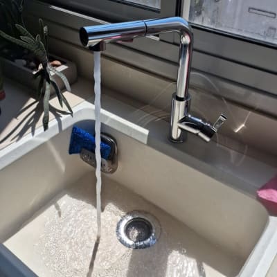 ברז מים זורם בכיור מטבח עם ספוג כחול