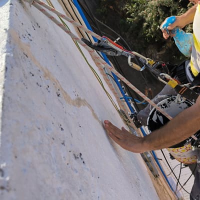 עובד בגובה עם קסדה אדומה, חבל וציוד בטיחות