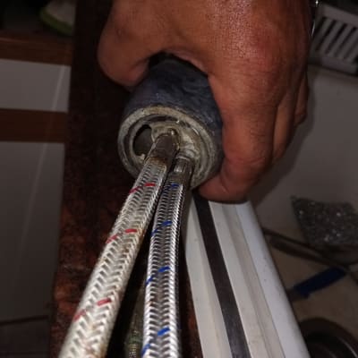 יד מחזיקה צינורות מתכת ליד כיור