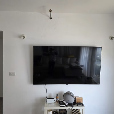 טלוויזיה תלויה על קיר עם שולחן קטן מתחת