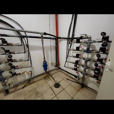 צינורות ומדידים בחדר טכני עם רצפה מרוצפת