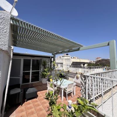 פרגולה מעץ מעל שולחן וכיסאות בגינה