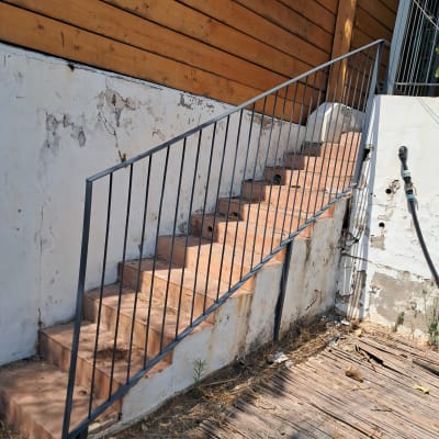 מדרגות עם מעקה מתכת ליד קיר עץ