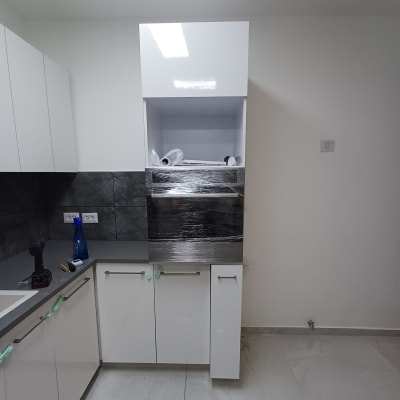 מטבח עם ארונות לבנים, כלים וציוד עבודה