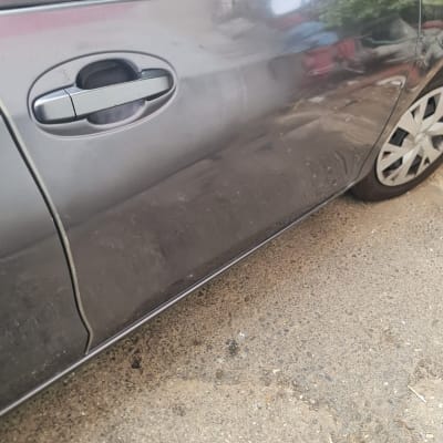 דלת רכב עם שריטות ולכלוך, גלגל קדמי נראה