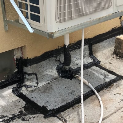 איטום צינורות ומזגן עם חומר שחור על גג