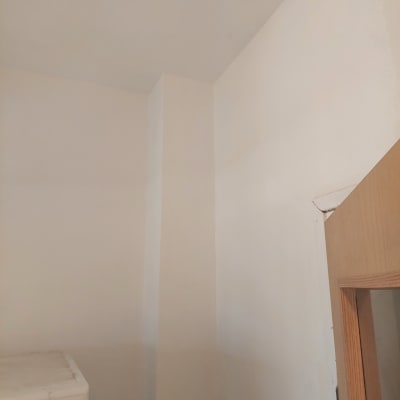 קיר צבוע בלבן עם דלת עץ בפינה