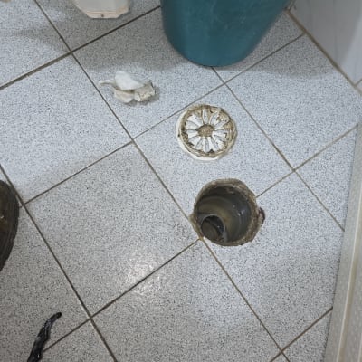 פתח ניקוז ברצפה עם מכסה פתוח וכלי עבודה