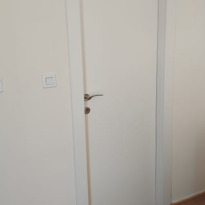 דלת לבנה עם ידית מתכת על רצפת עץ