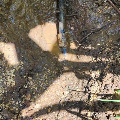 צינור מים חשוף באדמה רטובה עם חיבור מתכת