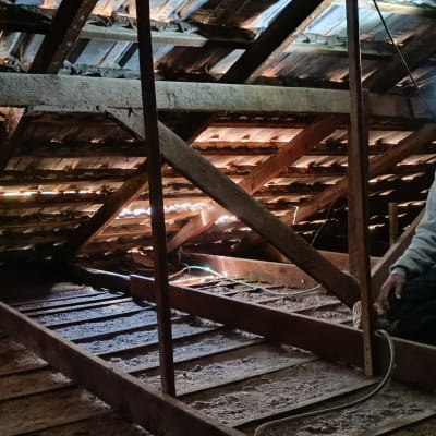 אדם עם פנס ראש בתוך עליית גג עם קורות עץ