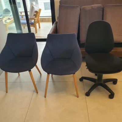 שני כיסאות כחולים וכיסא משרדי שחור על רצפה