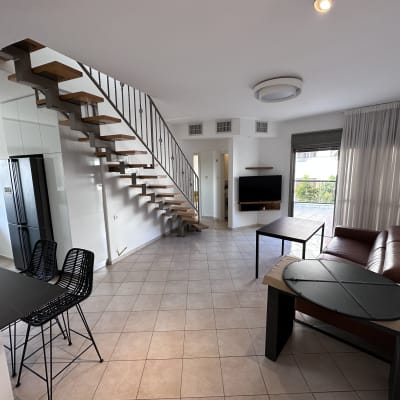 סלון מודרני עם ספה, שולחן ומדרגות עץ.