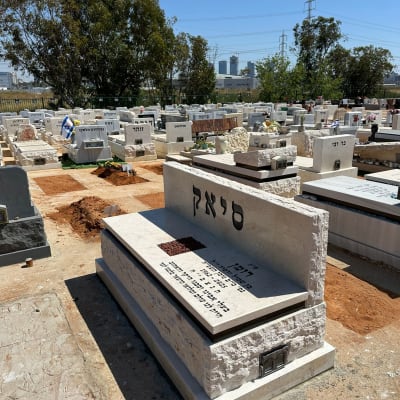 מצבות בבית קברות עם כיתוב בעברית ודגל ישראל