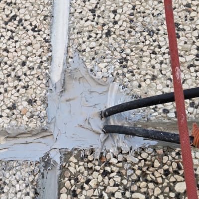 עבודת איטום על משטח חצץ עם צינורות