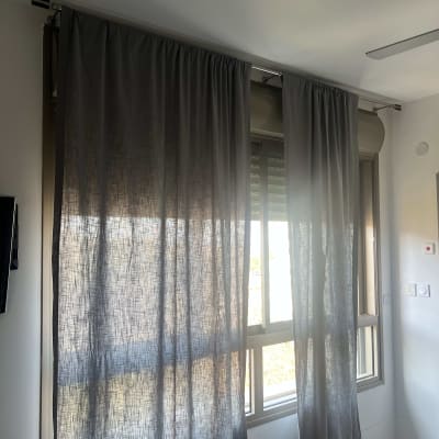 וילון אפור תלוי על מסילה מעל חלון