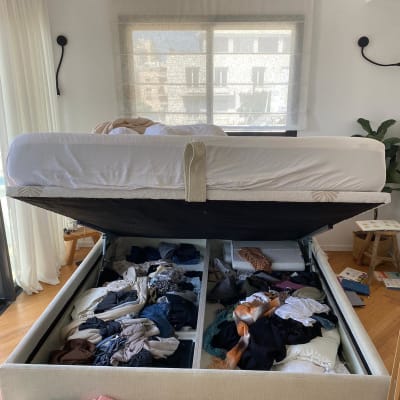 מיטה עם אחסון פתוח מלא בבגדים לא מסודרים