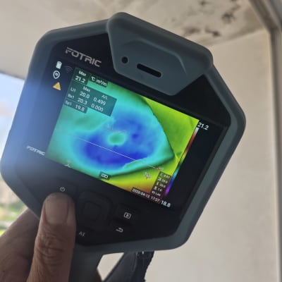 מד חום תרמי מציג נתונים על קיר עם סימני רטיבות