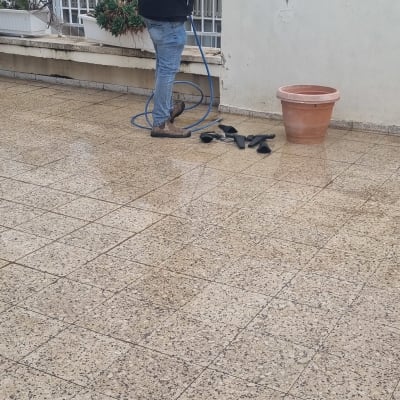 אדם עם צינור מים על גג מרוצף