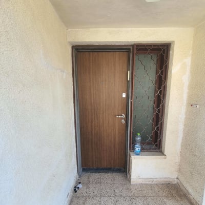 דלת עץ עם ידית מתכת, בקבוק על אדן החלון