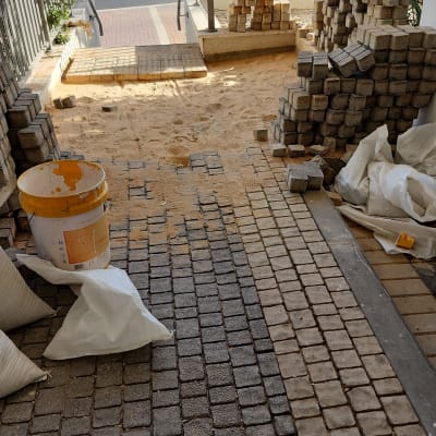 אבנים משתלבות, דלי צבע, שקי חול באתר בנייה