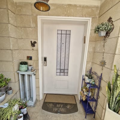 כניסה לבית עם דלת לבנה וצמחים מסביב