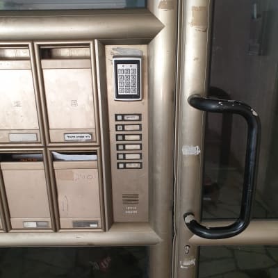 לוח מקשים אינטרקום ליד תיבות דואר על דלת כניסה