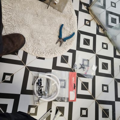 כלים וחלקים לעבודה בתחום האינסטלציה על רצפת חדר אמבטיה