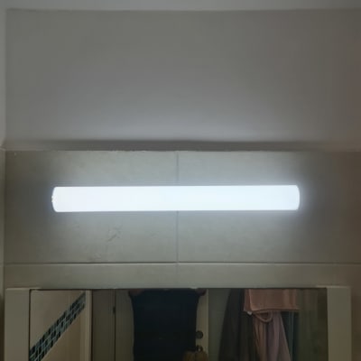 מנורת פלורסנט דולקת מעל מראה בחדר אמבטיה