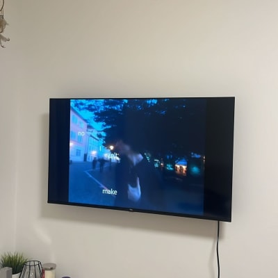 טלוויזיה תלויה על הקיר עם תמונה מטושטשת, שולחן קטן עם חפצים שונים