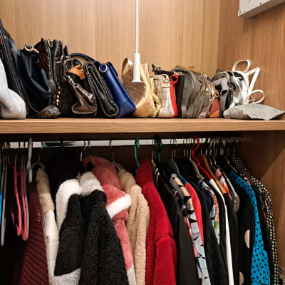 ארון בגדים עם תיקים על מדף ובגדים תלויים על קולבים