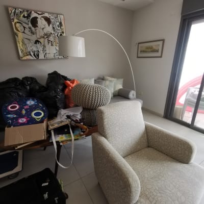 חדר עם כורסה, שולחן עמוס חפצים ושקיות שחורות