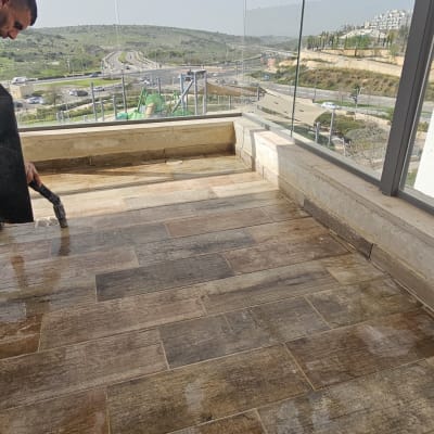 אדם מנקה מרפסת עם רצפת עץ ונוף פתוח