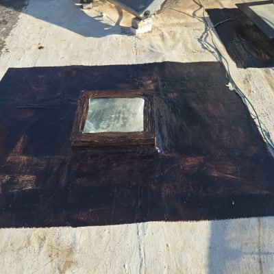 איטום גג עם חומר שחור סביב חלון מרובע