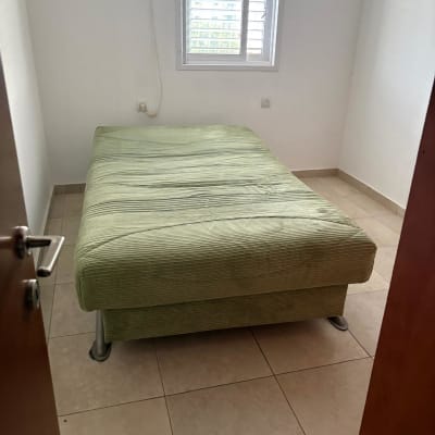 חדר ריק עם מיטה ירוקה וחלון