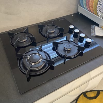 כיריים גז שחורות עם ארבעה מבערים וכפתורי שליטה