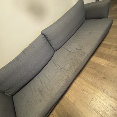 ספה אפורה עם כתמים על רצפת עץ