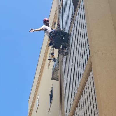 אדם עם קסדה על חבלים ליד רשת על בניין