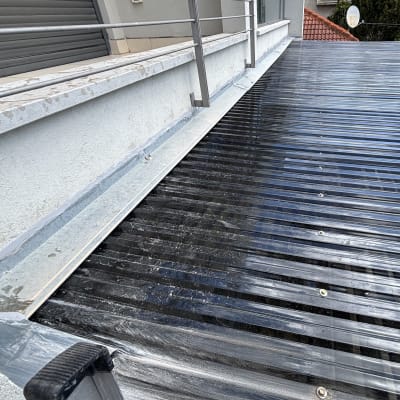 גג מתכת עם מעקה ומבנה סמוך