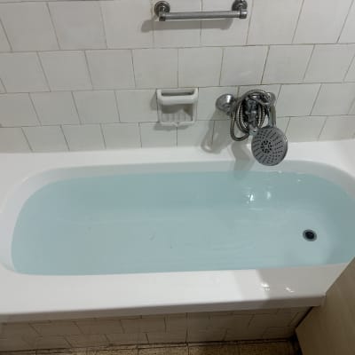 אמבטיה עם מים, אריחים לבנים וברז ידני