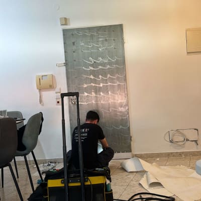 אדם עובד על דלת עם ציפוי שקוף וכלים מסביב