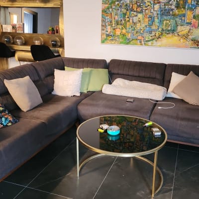 ספה אפורה עם כריות צבעוניות ושולחן זכוכית עגול