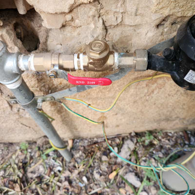 שסתום מתכת עם ידית אדומה וצינורות מחוברים