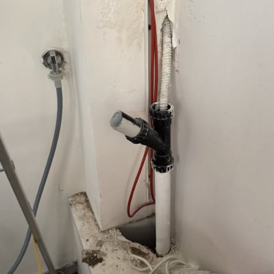 צינור פלסטיק לבן עם חיבורים שחורים בקיר