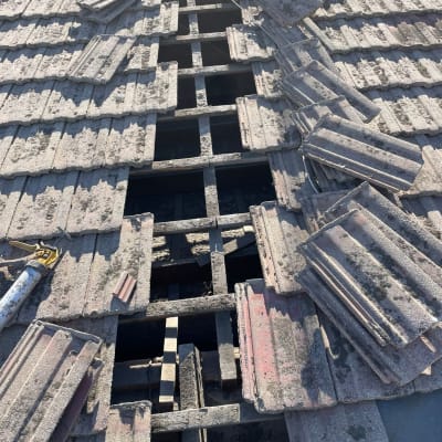 רעפים שבורים על גג עם קורות חשופות